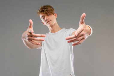 Yakışıklı duygusal genç stüdyoda griye karşı poz veriyor. 