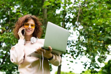 Dışarıda parkta dizüstü bilgisayarda çalışan bir kadın. 