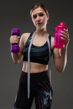 Güzel sporcu kadın griye karşı poz veriyor.