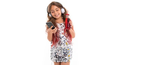 Girl in sparkling dress choosing song in black mobile phone and holding red plastic bottle with sipper isolated
