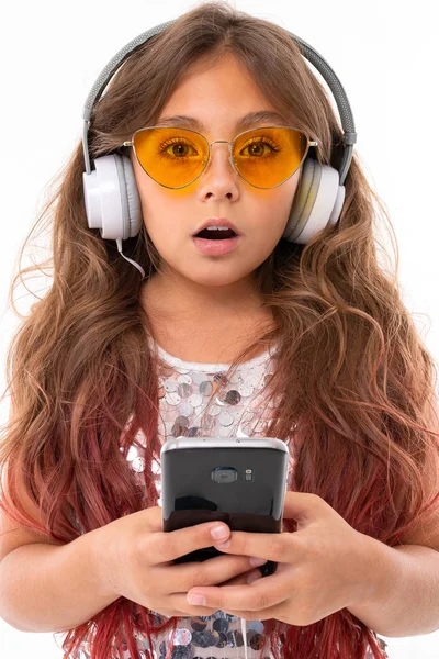Zaszokowana Dziewczyna Błyszczącej Sukience Żółtych Okularach Przeciwsłonecznych Dużymi Słuchawkami Trzymającymi — Zdjęcie stockowe