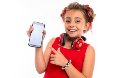 Beyaz arka planda cep telefonuyla poz veren sevimli küçük kız.  