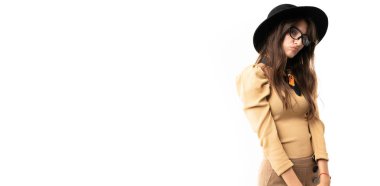 Stüdyoda güzel bir kadın beyaz şapkalı ve gözlükle poz veriyor. 