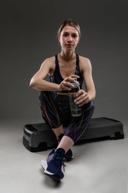 Güzel sporcu kadın griye karşı poz veriyor.