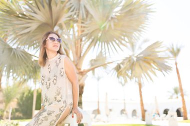 Palmiye ağaçlarının yanında poz veren güzel bir kadın.