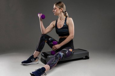 Güzel sporcu kadın griye karşı poz veriyor.