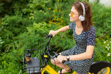 Bisikletli, kulaklık takan genç bir kadın.