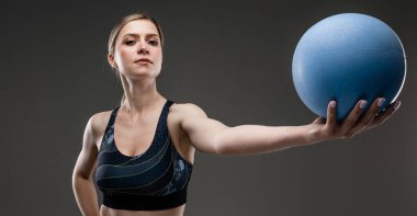 Güzel sporcu kadın griye karşı poz veriyor. 