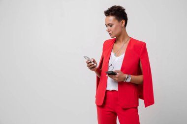 Kırmızı elbiseli iş kadını beyaz arka planda cep telefonuyla poz veriyor 