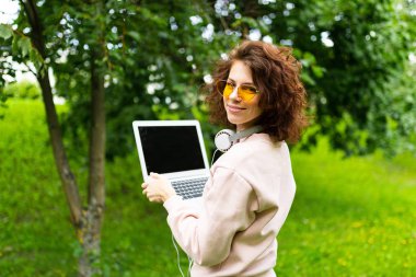 Dışarıda parkta dizüstü bilgisayarda çalışan bir kadın. 