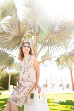 Palmiye ağaçlarının yanında poz veren güzel bir kadın.
