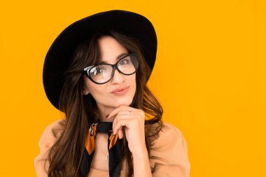 Stüdyoda turuncuya karşı poz veren şapkalı güzel bir kadın. 