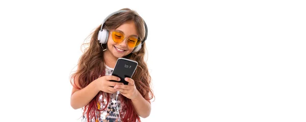 반짝이는 드레스와 선글라스를 커다란 이어폰으로 음악을 휴대폰으로 무언가를 타이핑하는 소녀의 — 스톡 사진