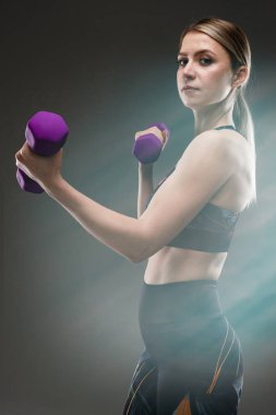 Güzel sporcu kadın griye karşı poz veriyor.