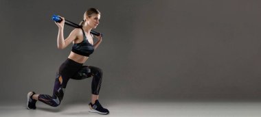 Güzel sporcu kadın griye karşı poz veriyor.