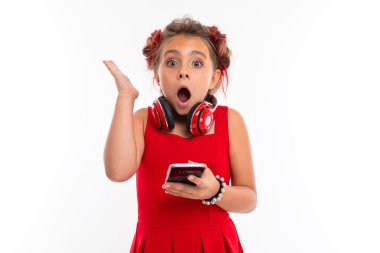 Beyaz arka planda cep telefonuyla poz veren sevimli küçük kız.  