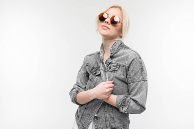 Arka planda güneş gözlüğü takan, kot ceketli neşeli, sarışın kızın portresi.