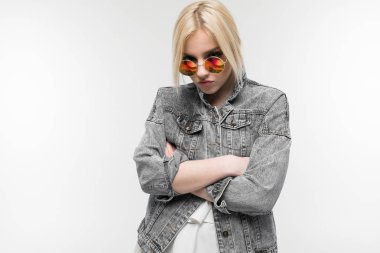 Arka planda güneş gözlüğü takan, kot ceketli neşeli, sarışın kızın portresi.