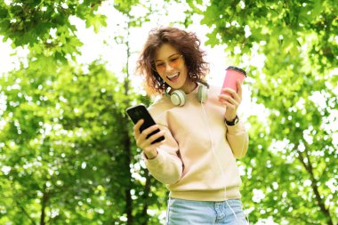 Parkta telefonu ve kahvesi olan güzel bir kadın.