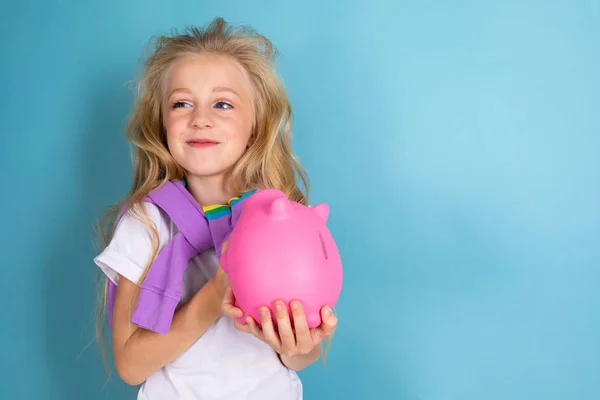 Nettes Kleines Mädchen Mit Sparschwein Posiert Gegen Blau — Stockfoto