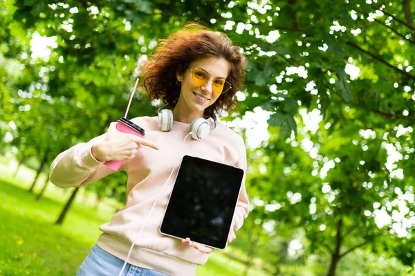 young woman with tablet pc in park