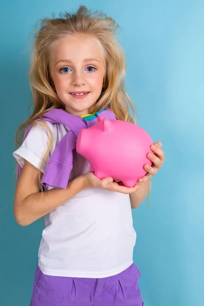 Linda Niña Con Alcancía Posando Contra Azul —  Fotos de Stock