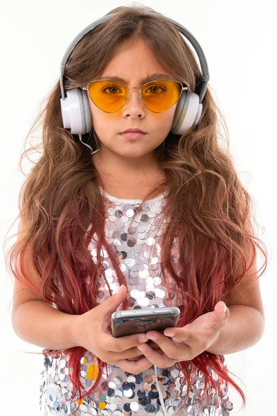 Niezadowolona Dziewczyna Błyszczącej Sukience Żółtych Okularach Przeciwsłonecznych Dużymi Słuchawkami Trzymającymi — Zdjęcie stockowe