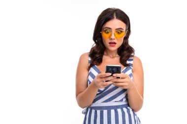 Telefonu güneş gözlüğü ve çizgili elbise takan genç bir kadın.