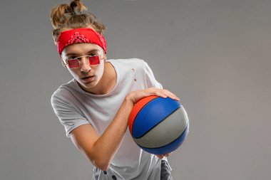 Serin tenager çocuk topuyla griye karşı duruyor. 