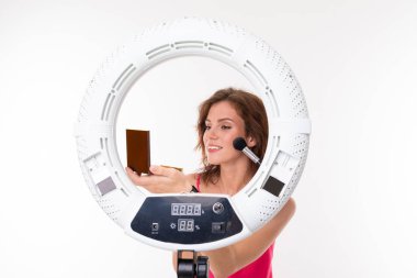 Genç bir kadın aynaya makyaj yapıyor. 