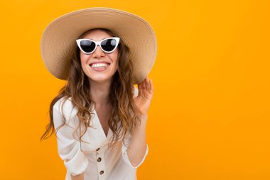 Şapkalı kadın turuncu arka planda poz veriyor. 