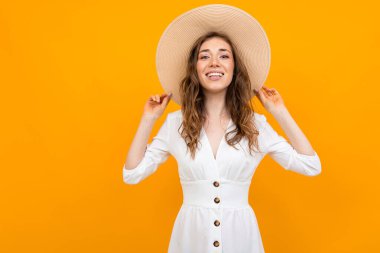 Şapkalı kadın turuncu arka planda poz veriyor. 