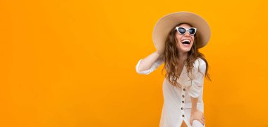 Şapkalı kadın turuncu arka planda poz veriyor. 