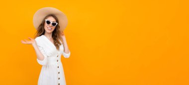 Şapkalı kadın turuncu arka planda poz veriyor. 