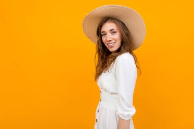 Şapkalı kadın turuncu arka planda poz veriyor. 