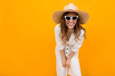 Şapkalı kadın turuncu arka planda poz veriyor. 