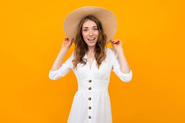 Şapkalı kadın turuncu arka planda poz veriyor. 