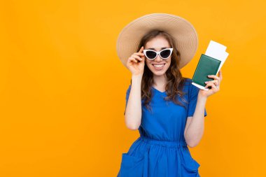 Pasaportu turuncu arka planda olan kadın. 