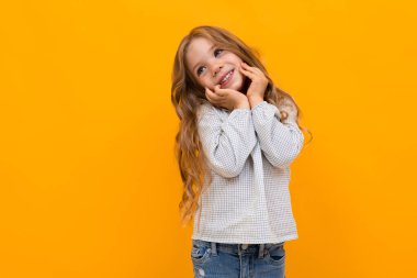 cute little girl posing against orange background