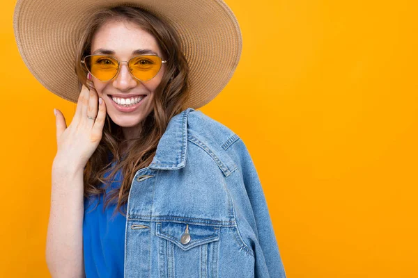 Frau Kleid Und Sommermütze Posiert Mit Jeansjacke Vor Orangefarbenem Hintergrund — Stockfoto