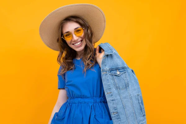 Frau Kleid Und Sommermütze Posiert Mit Jeansjacke Vor Orangefarbenem Hintergrund — Stockfoto