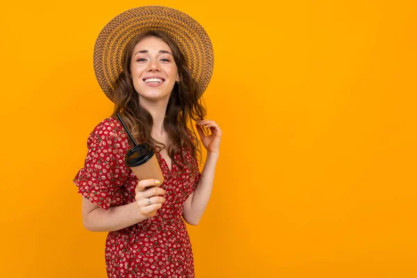 woman in red dress with print and straw hat with coffee