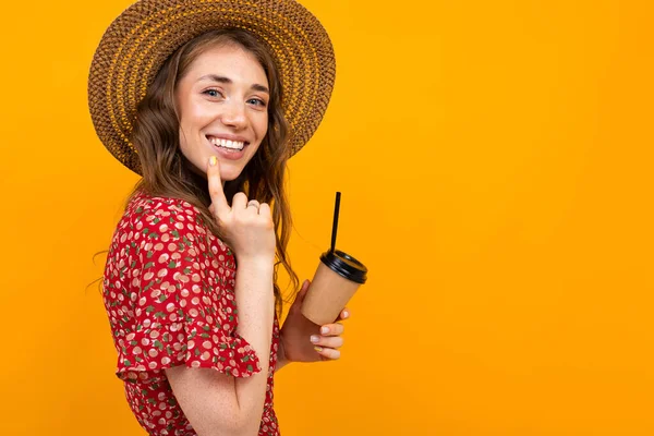 woman in red dress with print and straw hat with coffee