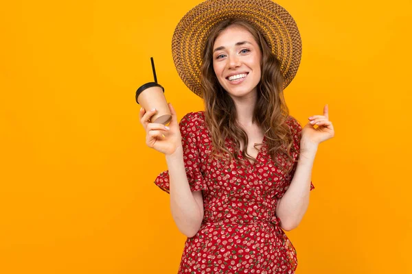 woman in red dress with print and straw hat with coffee