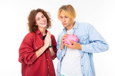 Woman and man posing with piggy bank against white background 