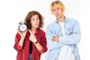 Woman and man posing against with alarm clock white background 