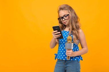 Telefonu ve mikrofonu olan küçük kız.