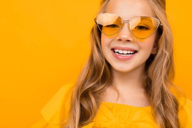Turuncu güneş gözlüğü takan hoş, şık bir kızın portresi. 