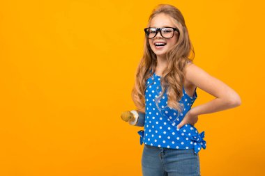 Turuncu arka planda mikrofonla poz veren tatlı küçük kız. 