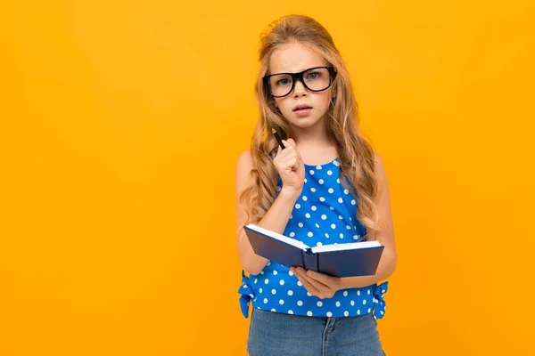 Liten Smart Flicka Poserar Med Glasögon Och Anteckningsbok Mot Orange — Stockfoto